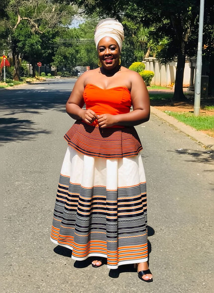 Off-shoulder striped maxi dress with orange bodice and navy, white, and orange skirt