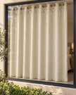 Cream eyelet curtains with abstract speckled pattern, hanging on bronze metal rings