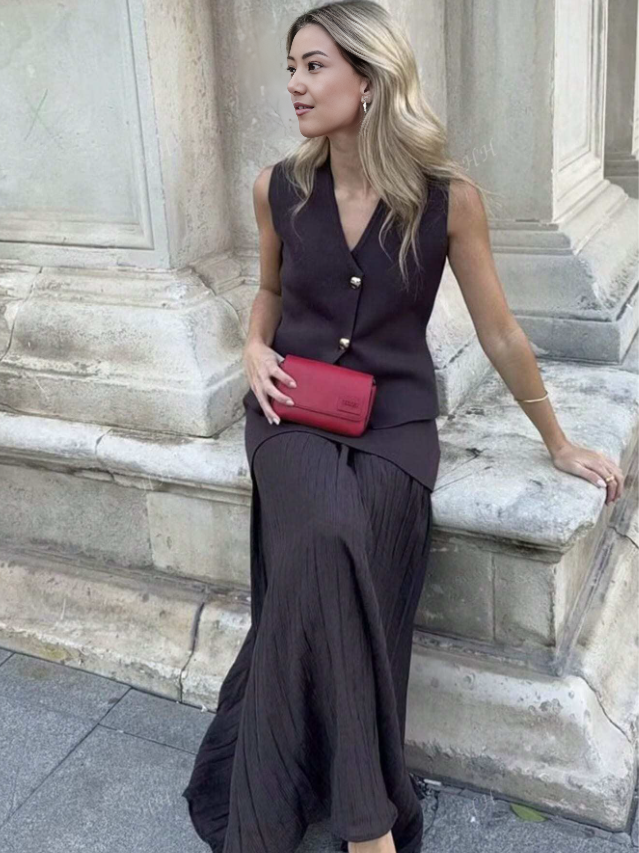 Dark maroon sleeveless vest with gold buttons and pleated midi skirt
