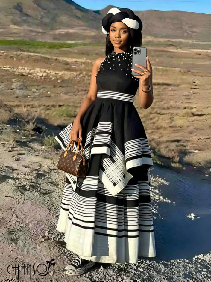 Black beaded sleeveless maxi dress with layered striped skirt, high neckline