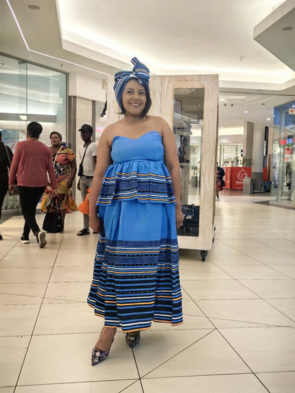 Strapless maxi dress with knotted blue headwrap; blue bodice and striped skirt