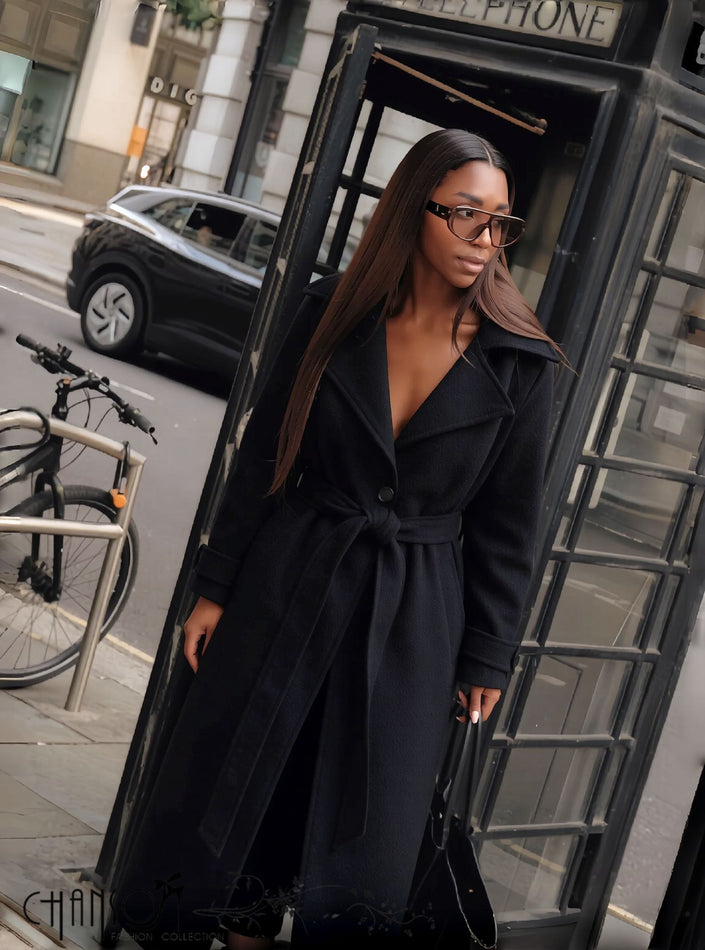 Black long belted coat with lapel collar and button front, side view