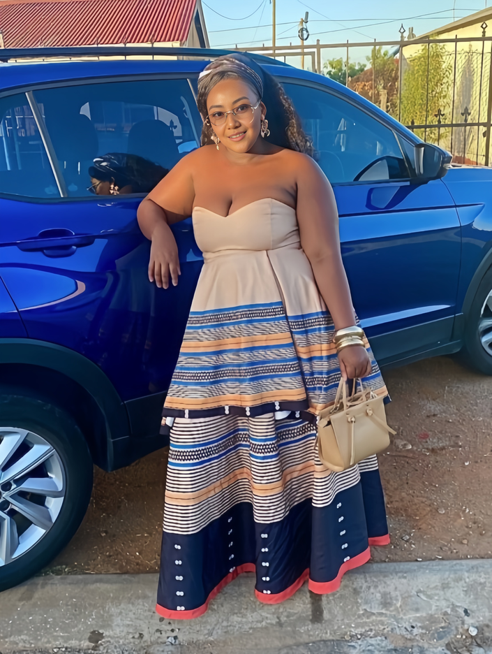 Strapless maxi dress with beige bodice and blue, tan, and red patterned skirt