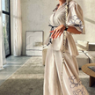 Cream wide-leg pants with large floral embroidery along the leg and side