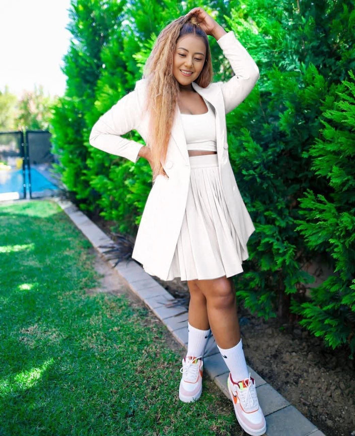 White relaxed blazer with pleated skirt set, standing side view