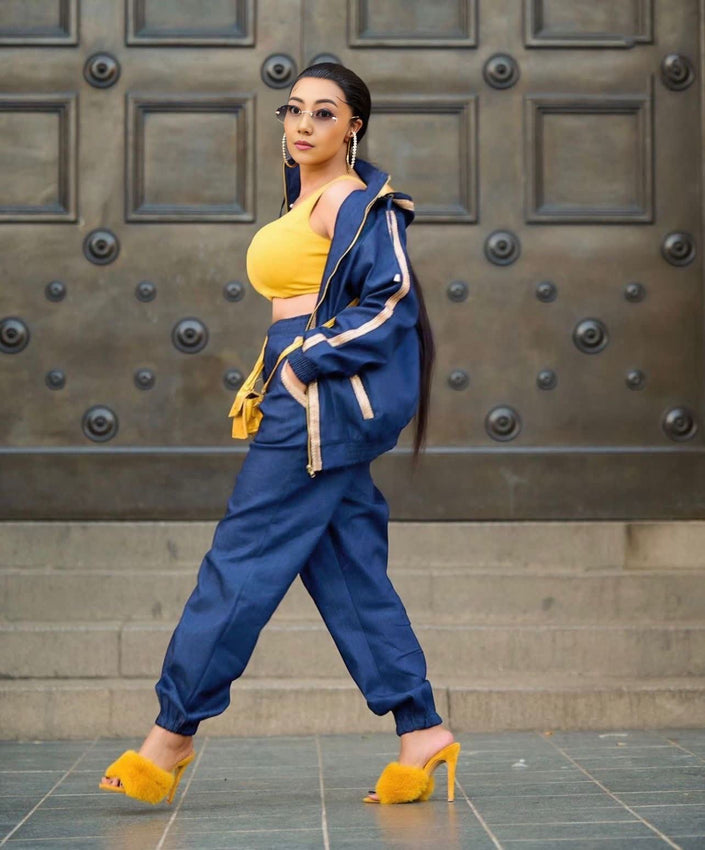 Blue jacket and trouser set with tie belt, worn with a yellow sleeveless top.
