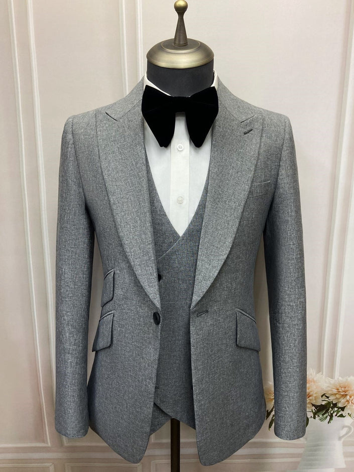Gray notched lapel blazer with button front and flap pockets, paired with black bow