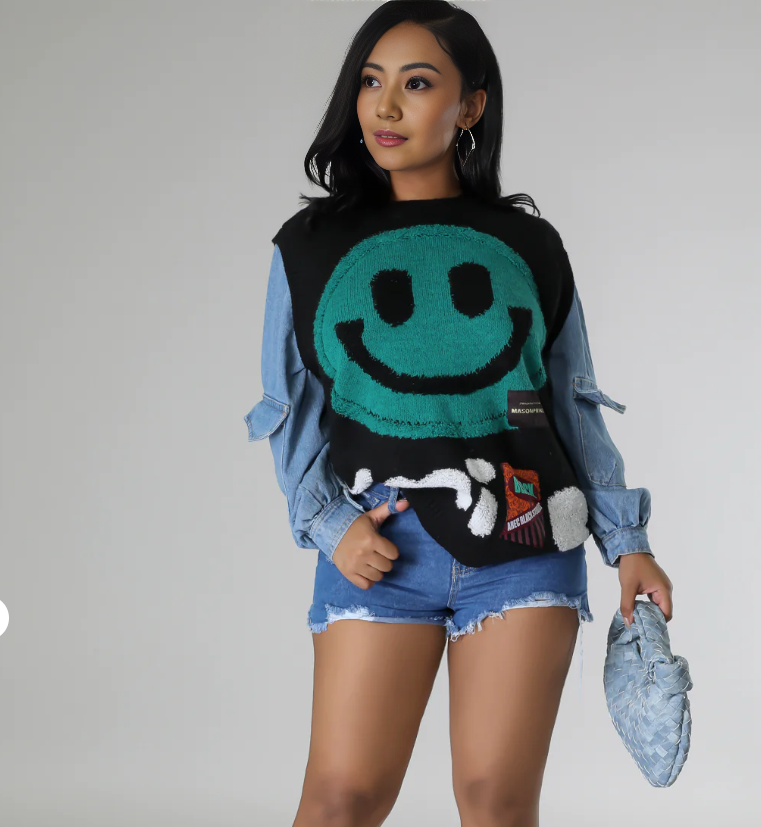 Black knit top with turquoise smiley graphic and ribbed hem