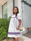 White puff-sleeve dress with blue panel stripes and red-and-blue hem border