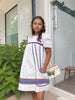 White puff-sleeve dress with blue panel stripes and red-and-blue hem border